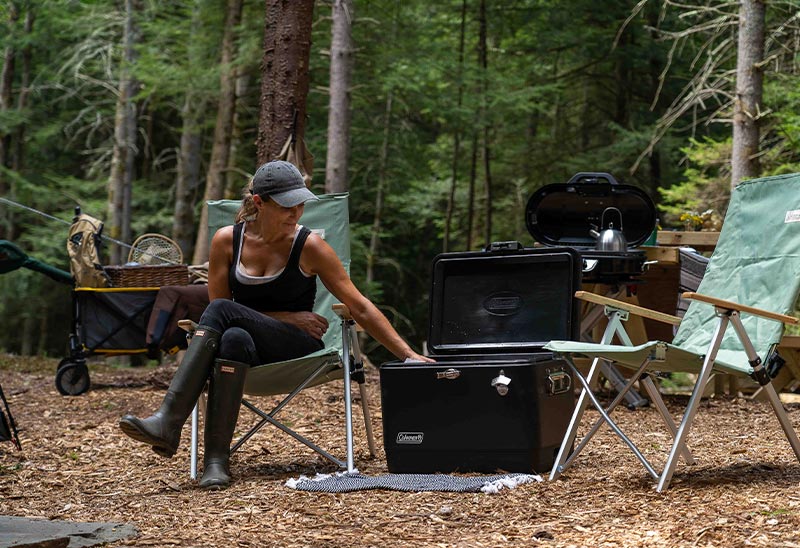 A couple sit outside their camping tent holding a map of hiking trails.